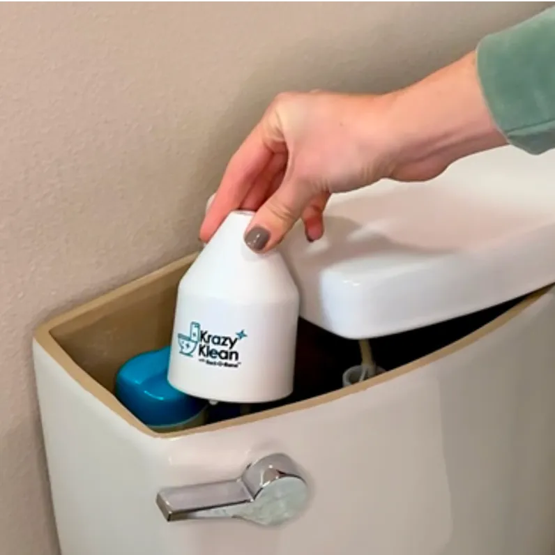 A hand places a white Krazy Klean container into the open tank of a toilet.