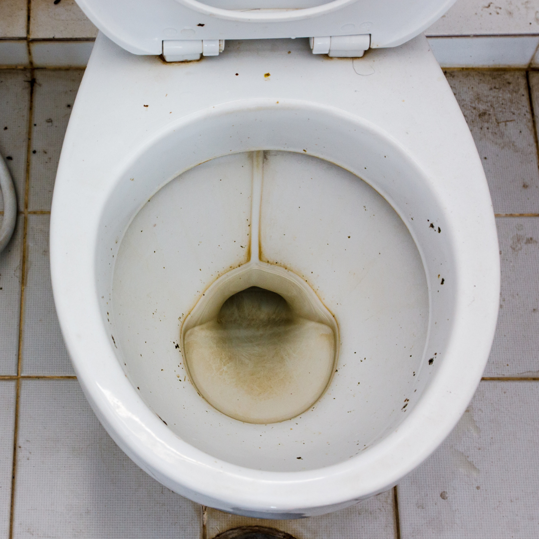 A hand places a white Krazy Klean container into the open tank of a toilet.